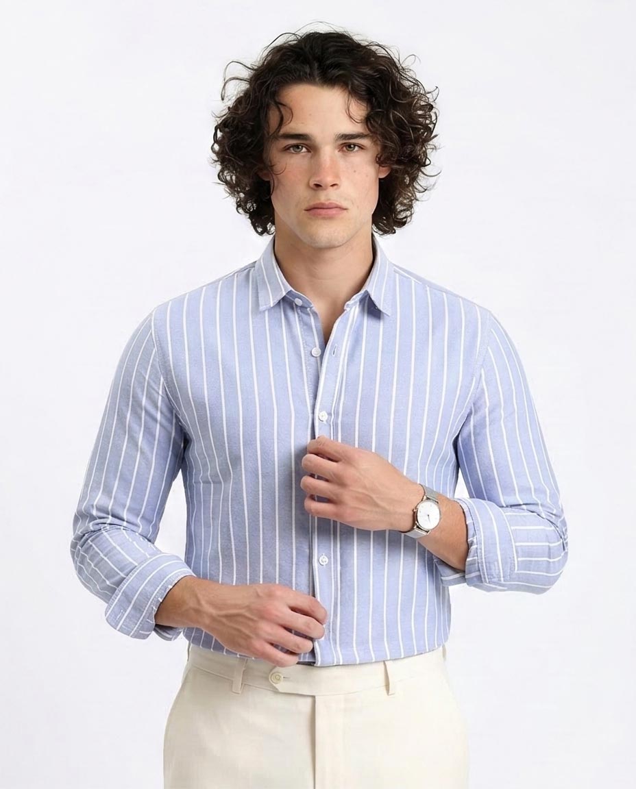 Man wearing a light blue striped shirt with rolled-up sleeves on a white background