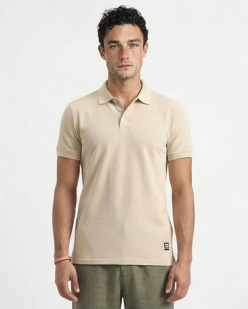 Man wearing a beige polo shirt against a white background