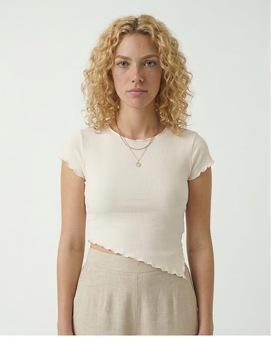 Woman wearing a white top with lace details on a plain background