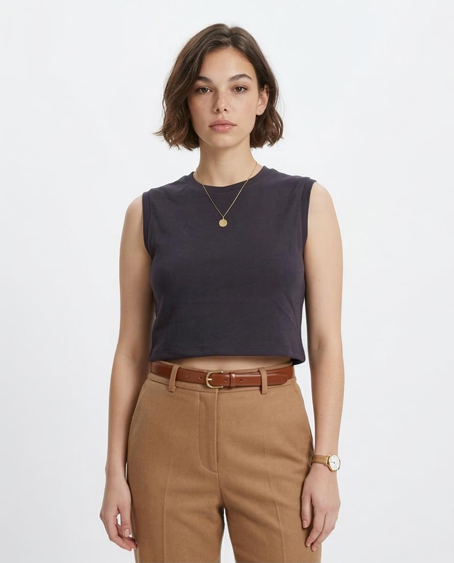 Woman wearing a dark sleeveless top and brown pants on a white background