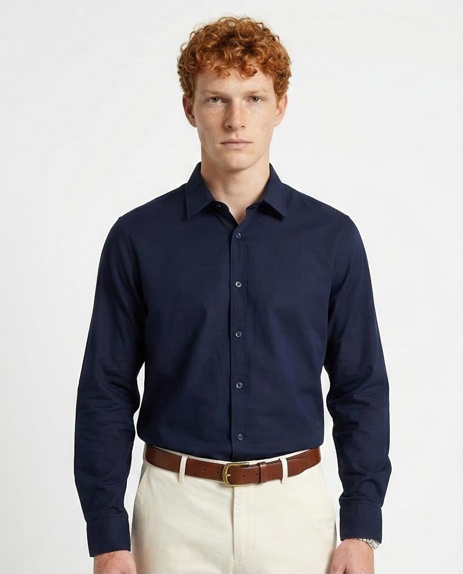 Man wearing a navy blue dress shirt and beige pants on a white background