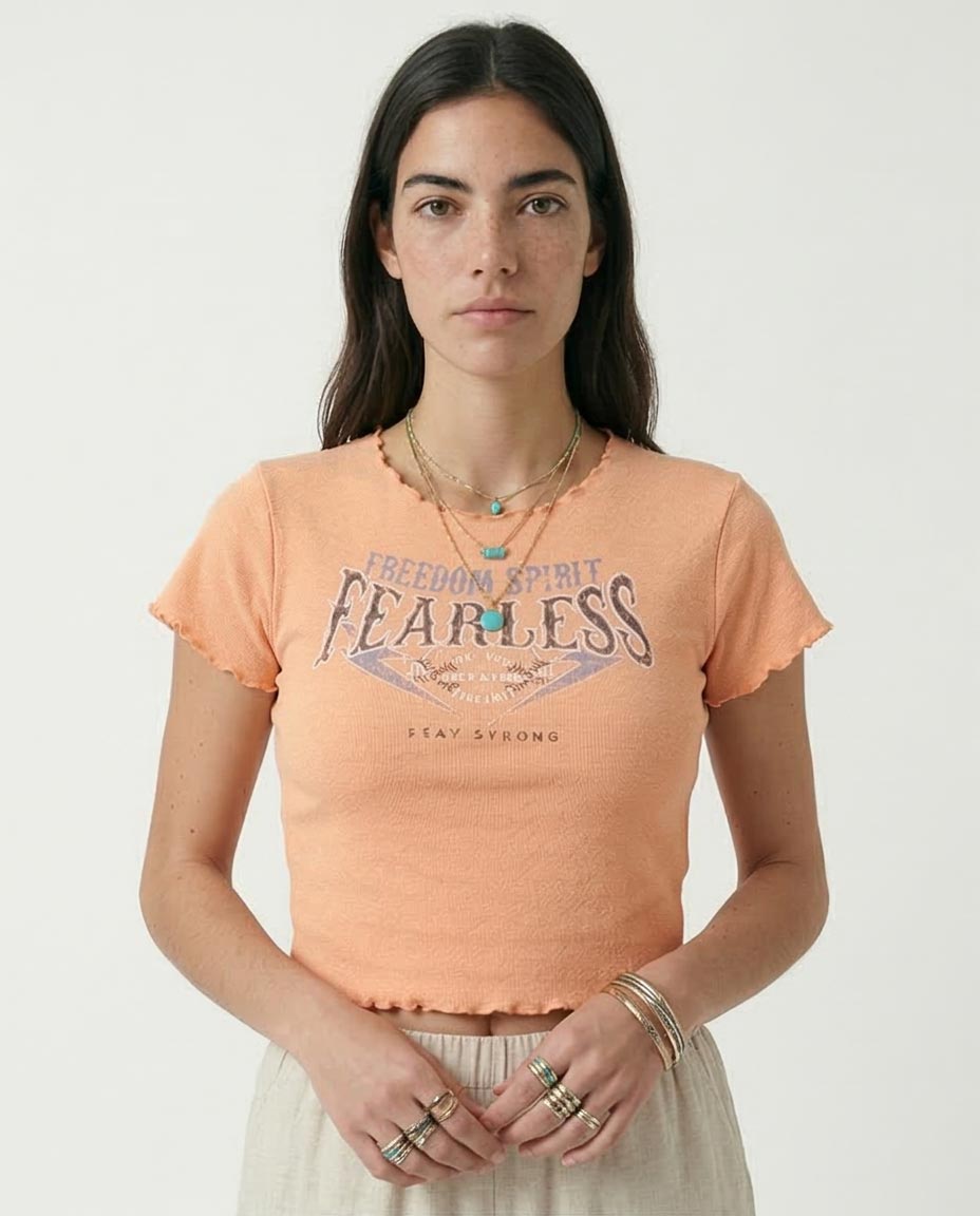 Woman wearing a peach-colored t-shirt with 'Freedom Spirit Fearless' text on a plain background
