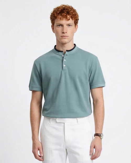 Man wearing a light blue polo shirt and white pants on a plain background