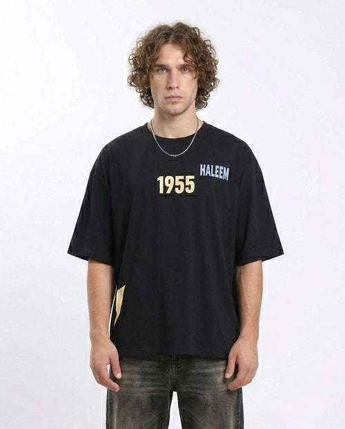 Person wearing a black t-shirt with 'Haleem 1955' text on a white background