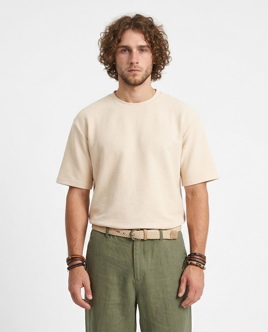 Man wearing a beige t-shirt and green pants on a plain background
