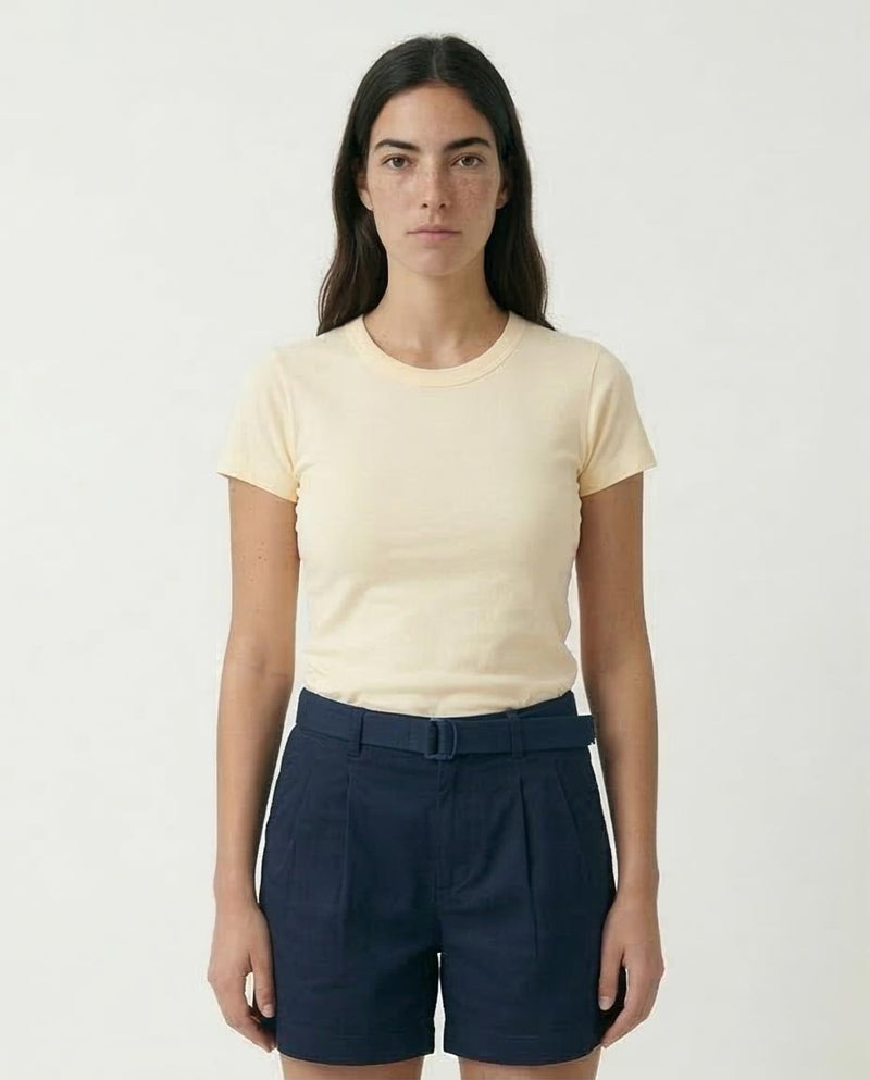 Woman wearing a beige t-shirt and navy shorts on a white background