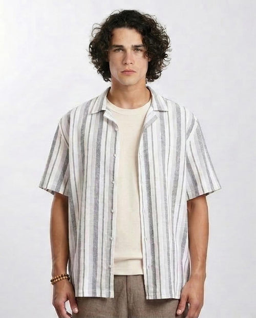 Man wearing a striped shirt over a plain shirt on a white background