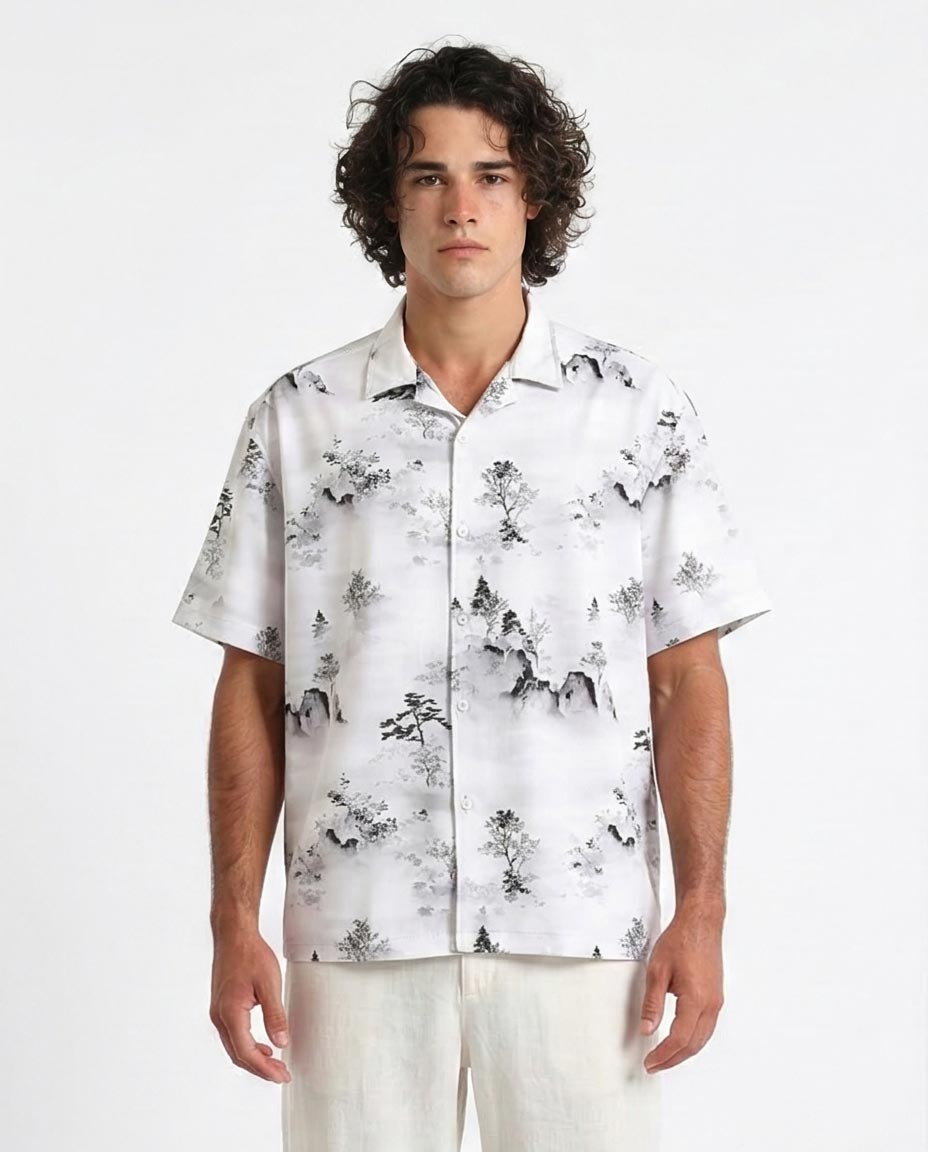 Man wearing a white shirt with black floral pattern on a plain background