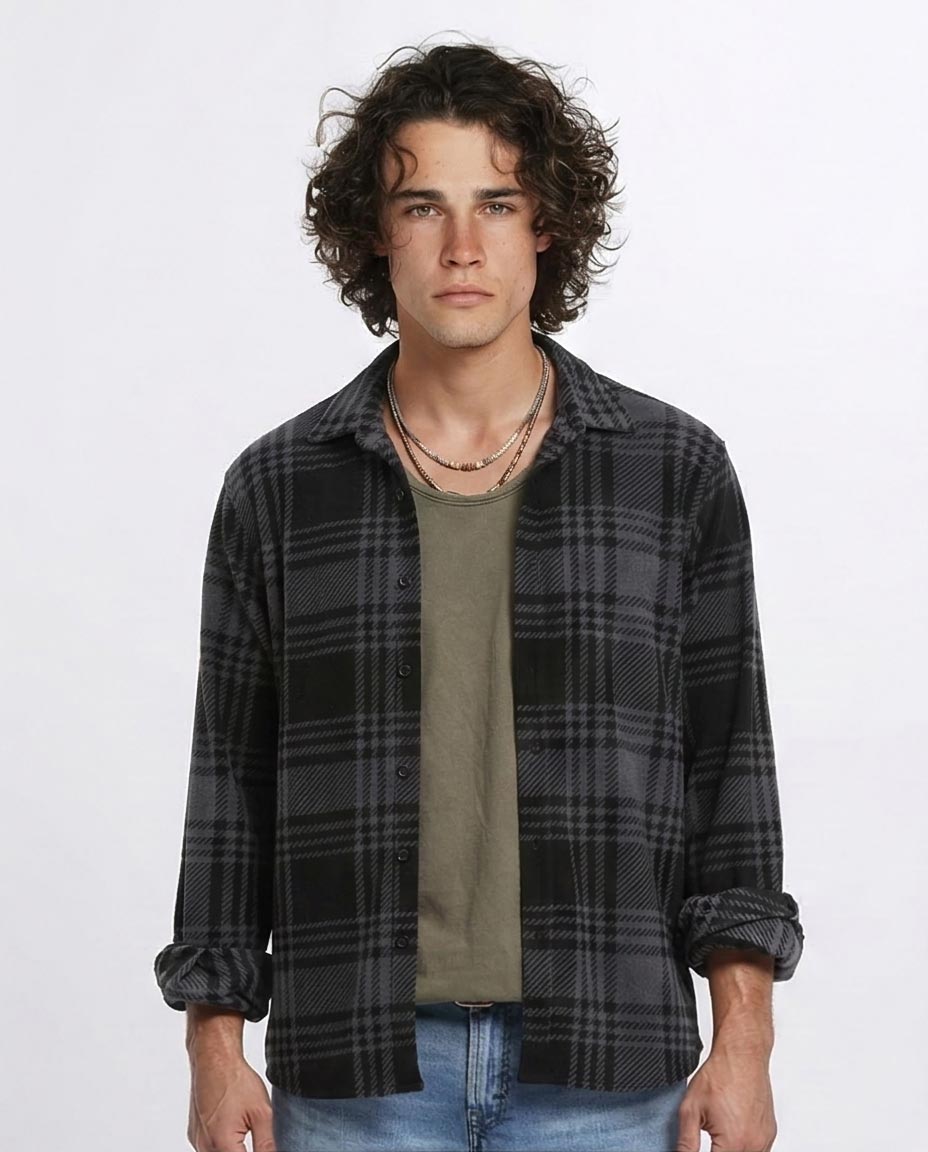 Man wearing a plaid shirt over a green t-shirt with a plain background
