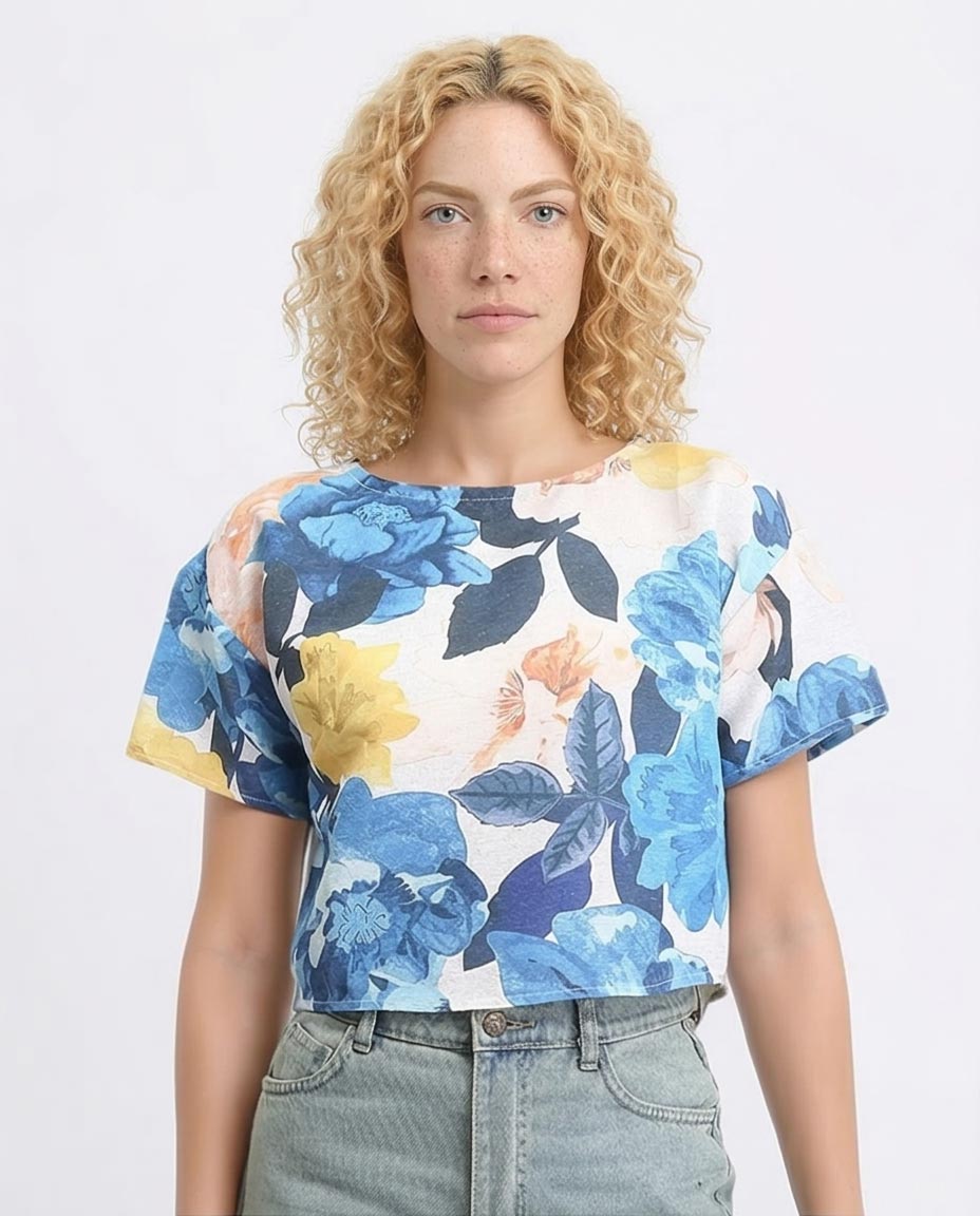 Woman wearing a floral top with blue, yellow, and white flowers on a plain background
