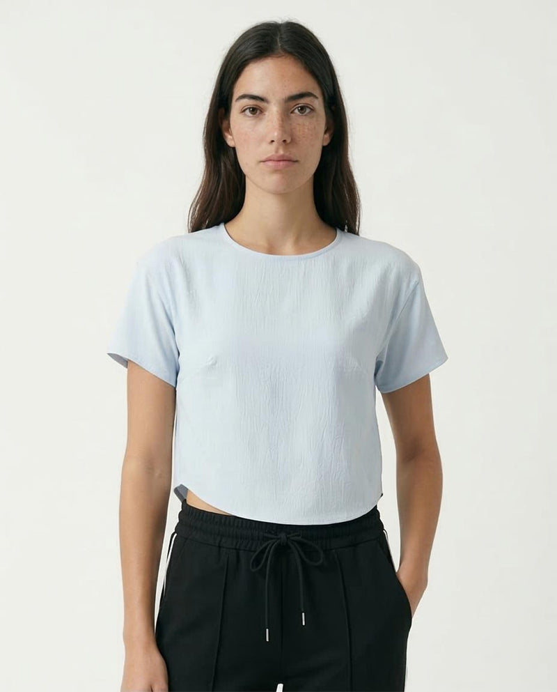 Woman wearing a light blue t-shirt and black pants on a white background