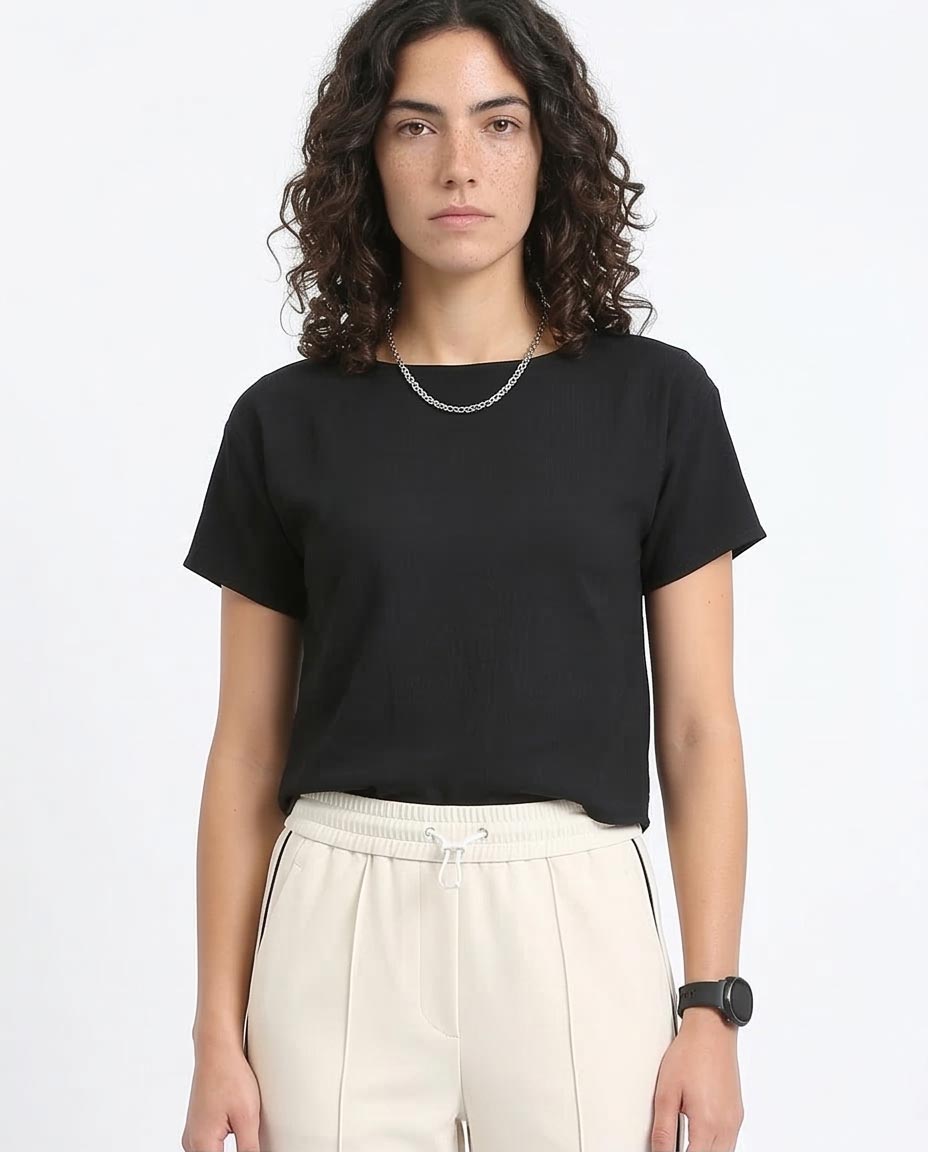 Woman wearing a black t-shirt and beige pants on a white background
