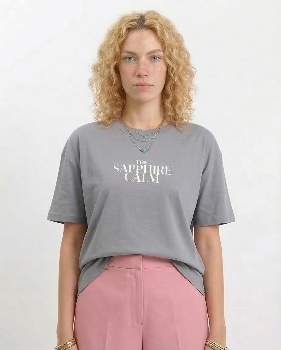 Woman wearing a gray t-shirt with 'The Sapphire Calm' text on a white background