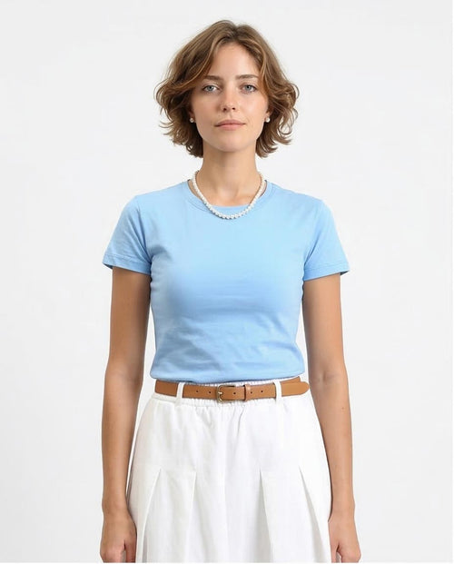 Woman wearing a light blue top and white pants on a plain background