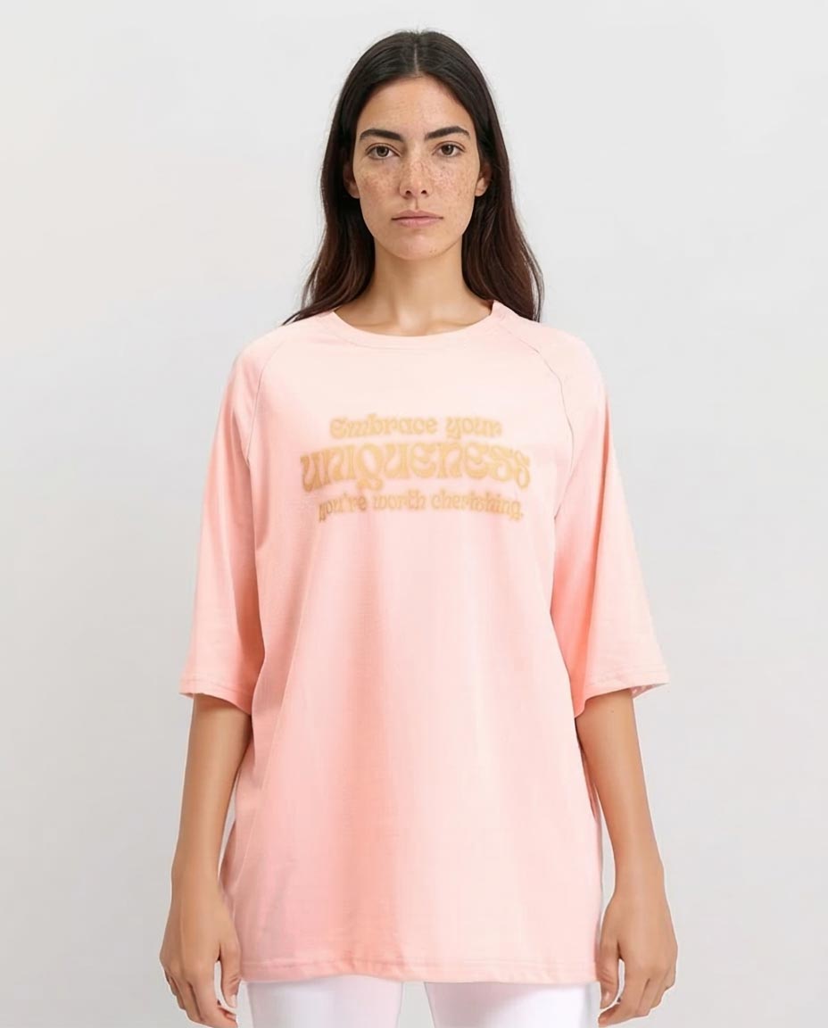 Woman wearing a light pink t-shirt with text on a plain background