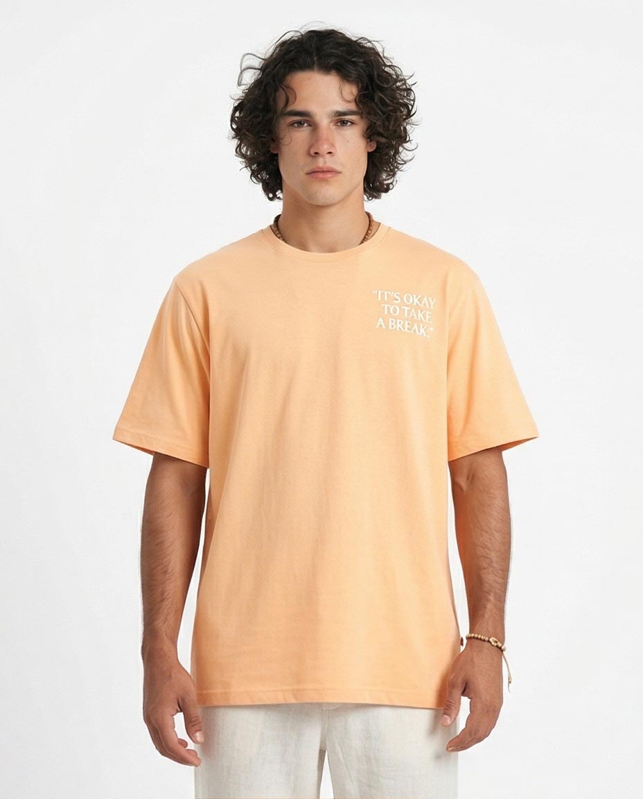 Man wearing a peach t-shirt with text on a white background