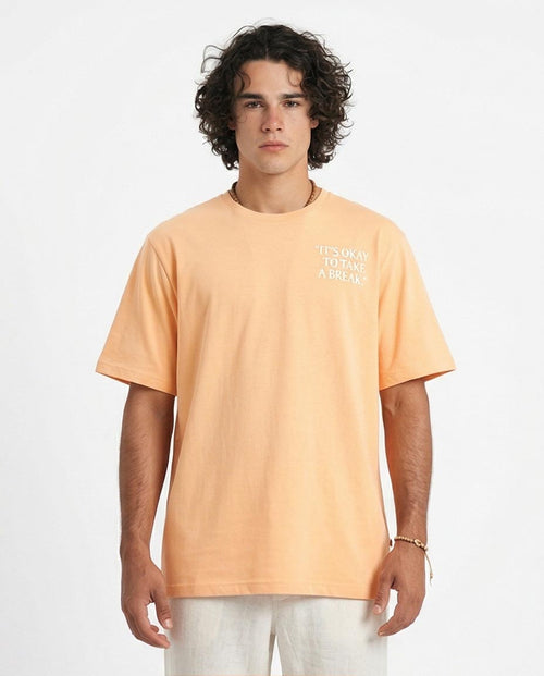 Man wearing a peach t-shirt with text on a white background