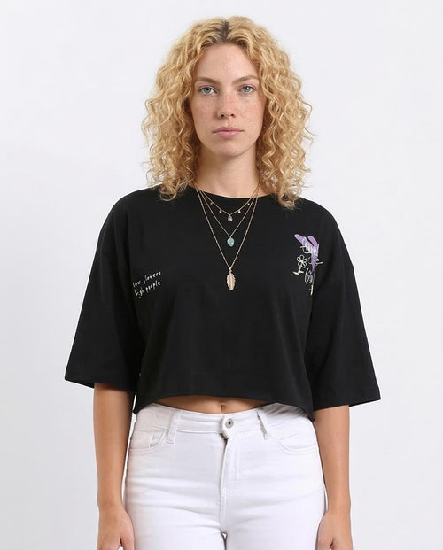 Woman wearing a black t-shirt with a graphic design and text, standing against a white background