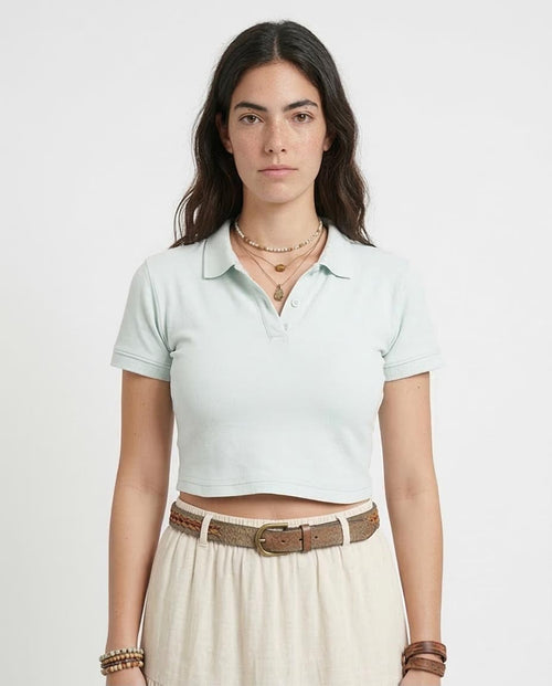 Woman wearing a light green polo shirt and beige skirt on a white background
