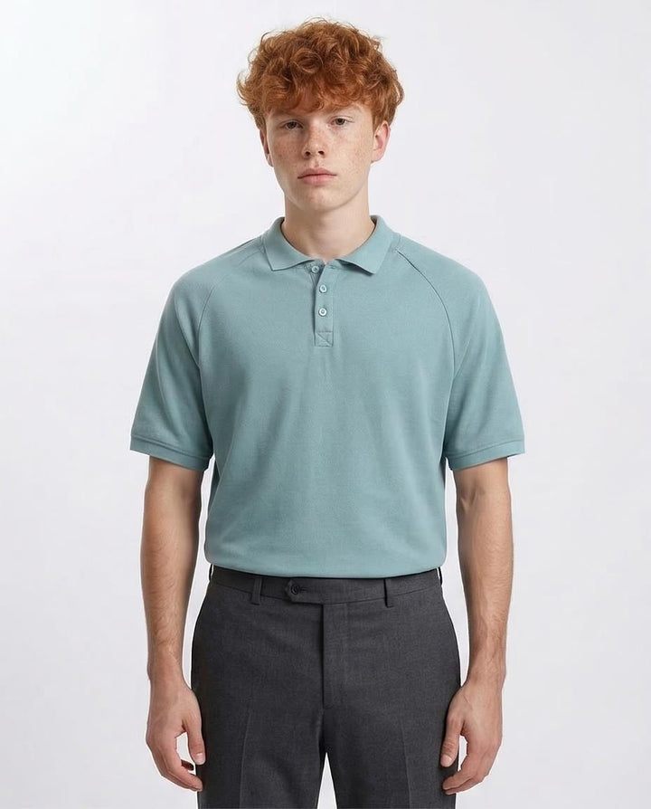Man wearing a light blue polo shirt and dark gray pants on a white background