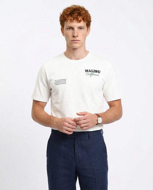 Man wearing a white t-shirt with 'Malibu California' text on a plain background