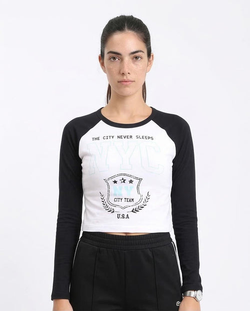 Woman wearing a black and white long-sleeve crop top with text and logo on a white background
