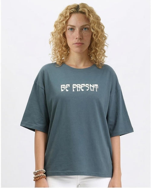 Women wearing a blue t-shirt with 'BE PRESENT' text on a plain background