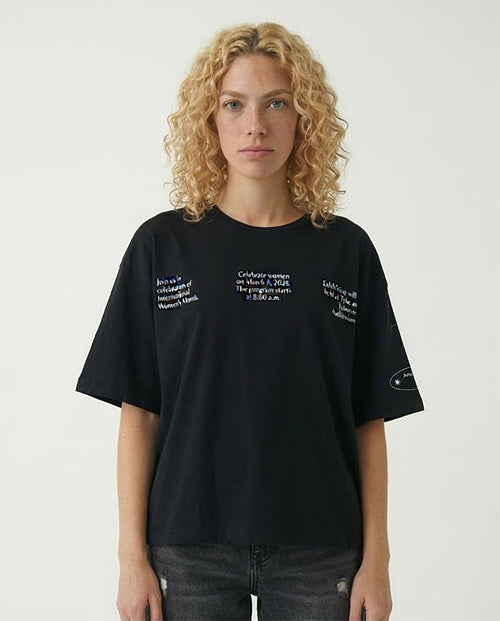 Woman wearing a black t-shirt with text on a plain background