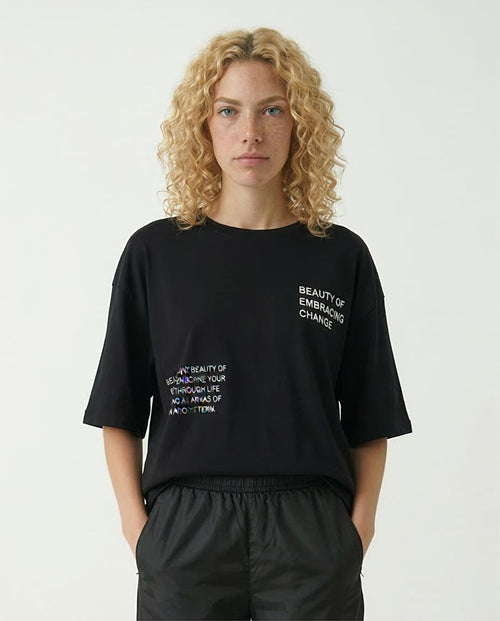 Person wearing a black t-shirt with text on a plain background