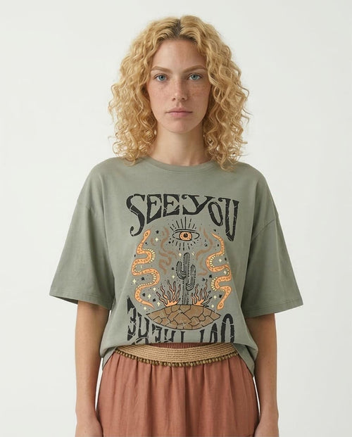 Woman wearing a green t-shirt with a graphic design and text on a plain background