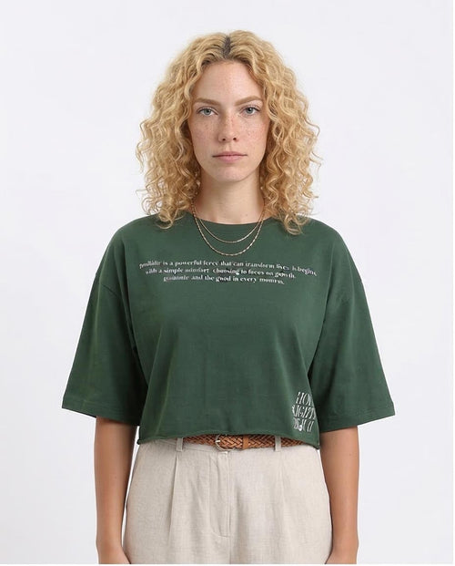 Woman wearing a green t-shirt with text on a plain background