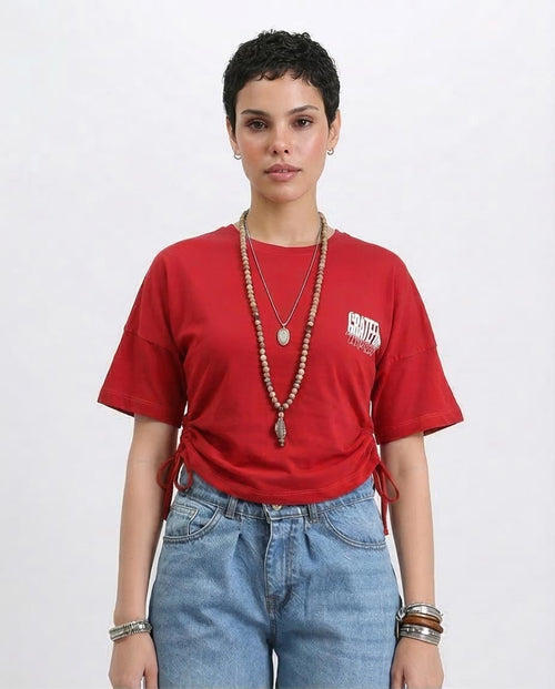 Woman wearing a red t-shirt with a logo and blue jeans on a white background