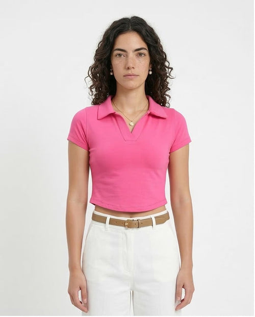 Woman wearing a pink polo shirt and white pants on a plain background