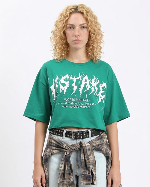 Woman wearing a green t-shirt with white text and graphics on a plain background