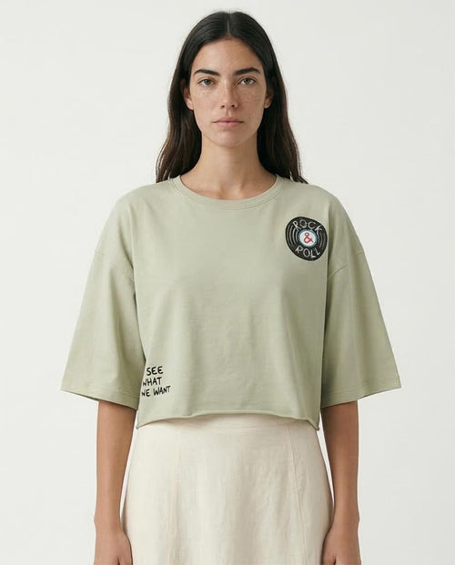 Woman wearing a light green t-shirt with text and a logo on a white background