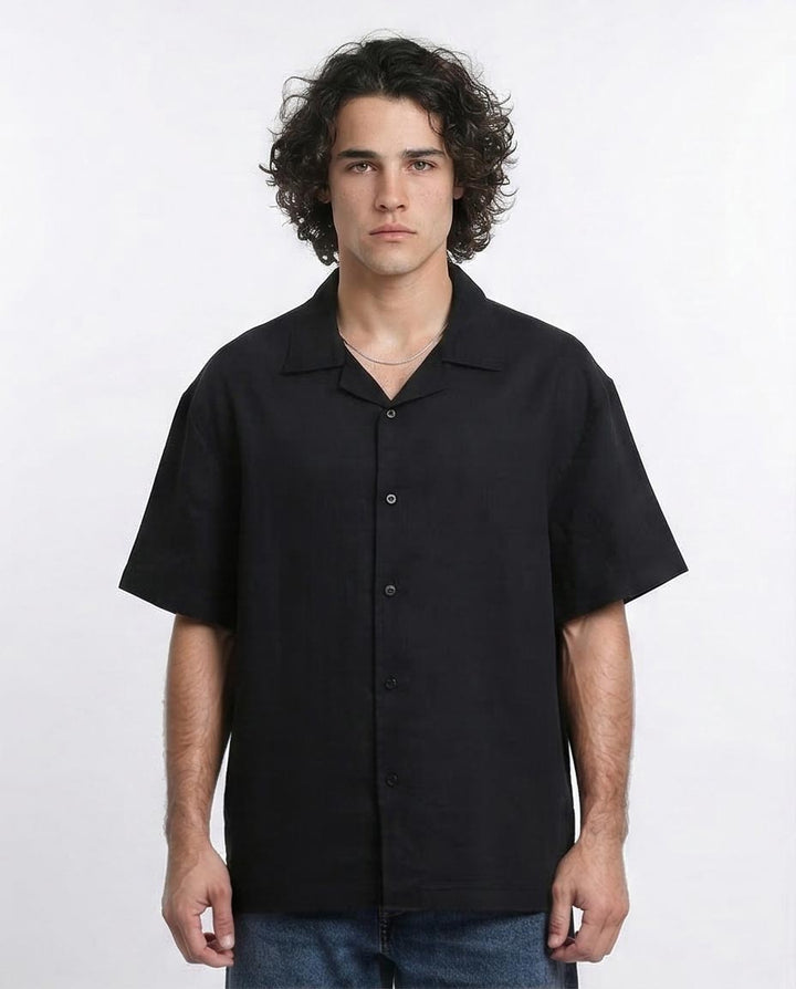 Man wearing a black short-sleeve button-up shirt against a white background