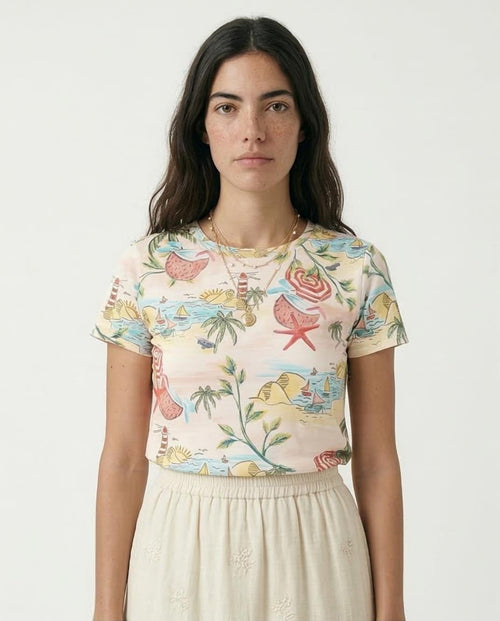 Woman wearing a colorful tropical-themed shirt with a plain background