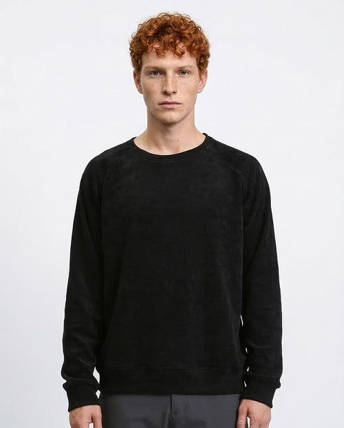 Man wearing a black sweatshirt against a plain background