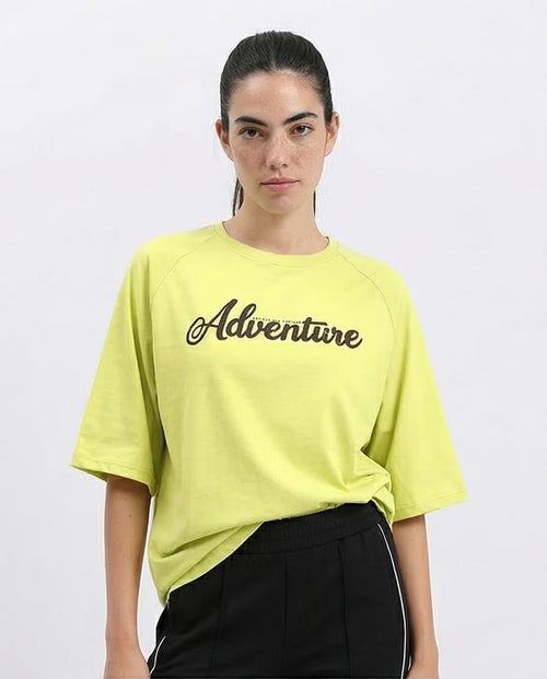 Woman wearing a bright yellow t-shirt with 'Adventure' text on a white background