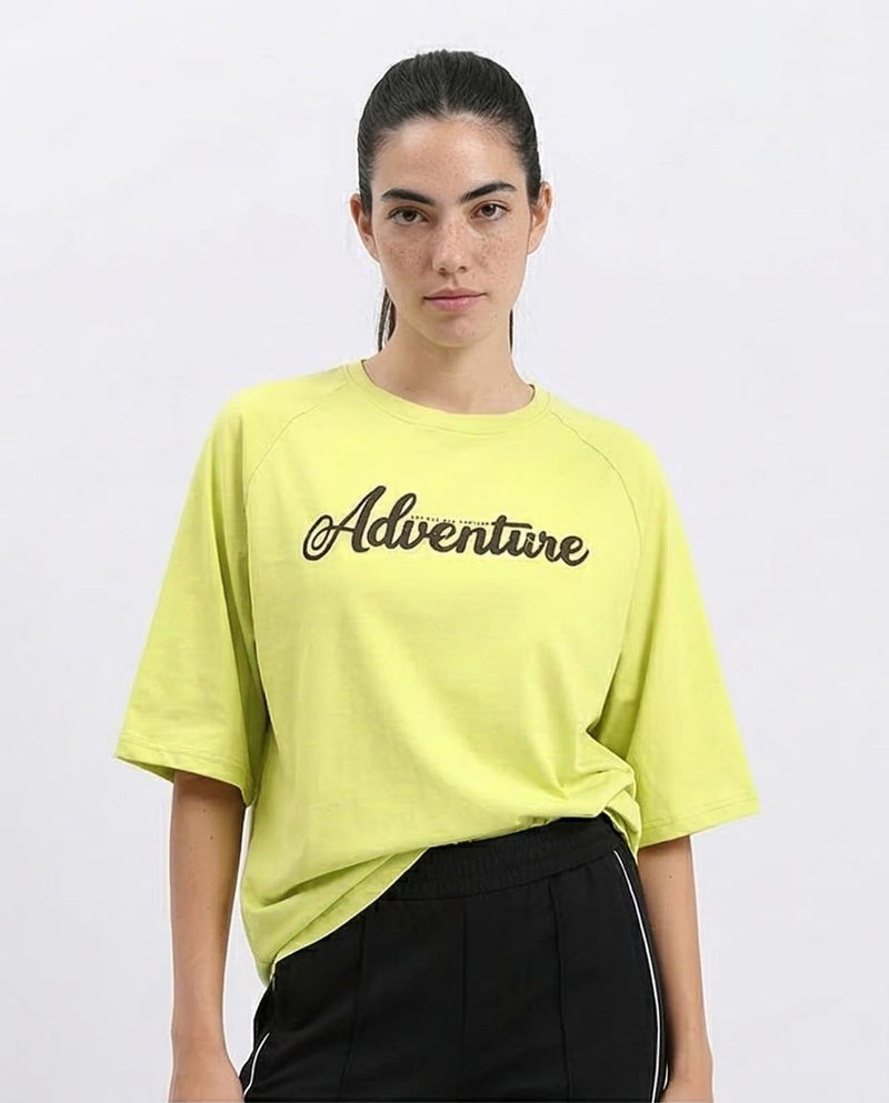 Woman wearing a bright yellow t-shirt with 'Adventure' text on a white background