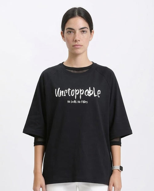 Person wearing a black oversized t-shirt with 'Unstoppable' text on a white background