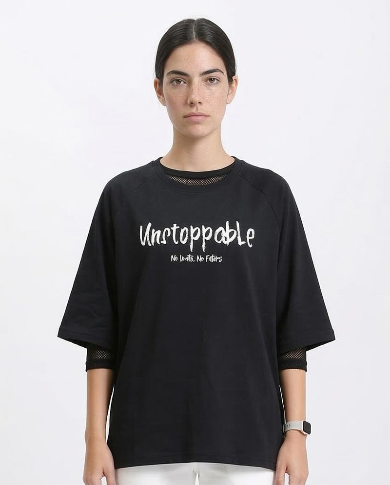 Person wearing a black oversized t-shirt with 'Unstoppable' text on a white background