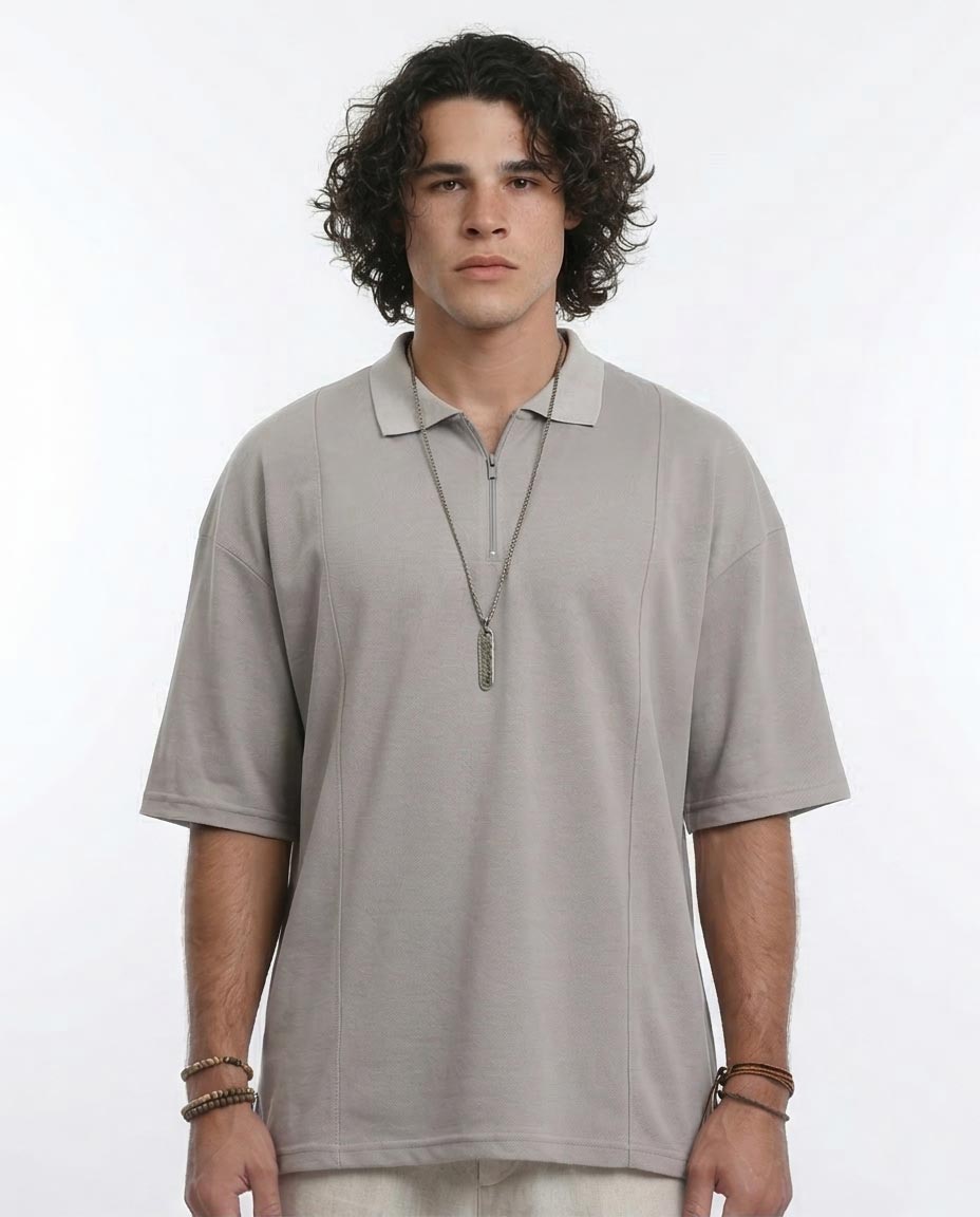 Man wearing a light gray polo shirt with a necklace on a white background