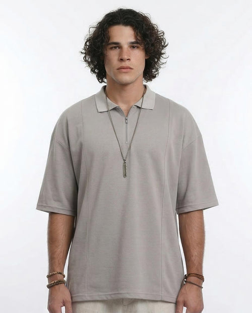 Man wearing a light gray polo shirt with a necklace on a white background