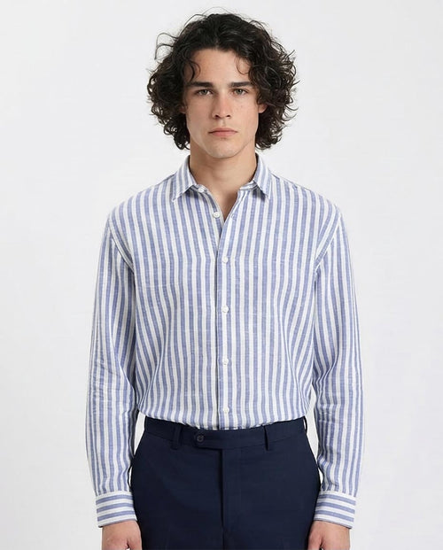 Man wearing a blue and white striped shirt with dark pants on a light gray background