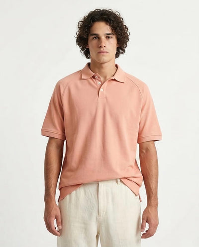 Man wearing a pink polo shirt and light-colored pants on a white background