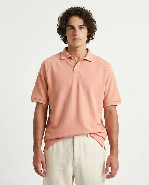 Man wearing a pink polo shirt and light-colored pants on a white background