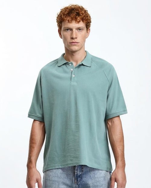 Man wearing a light green polo shirt on a white background