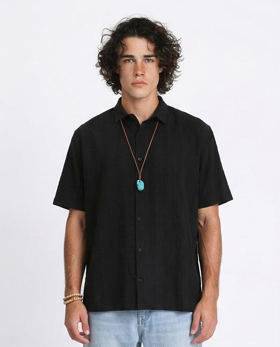 Man wearing a black short-sleeve shirt with a necklace on a white background