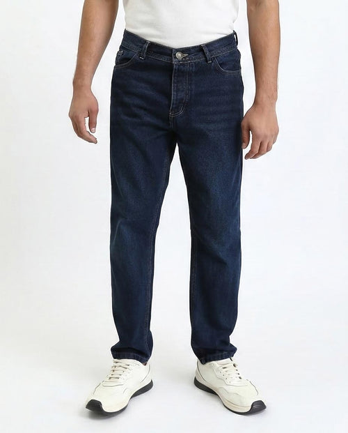 Person wearing dark blue jeans and white sneakers on a white background